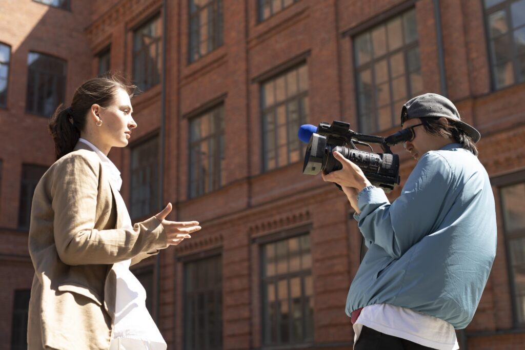 Videographer filming woman speaking outdoors