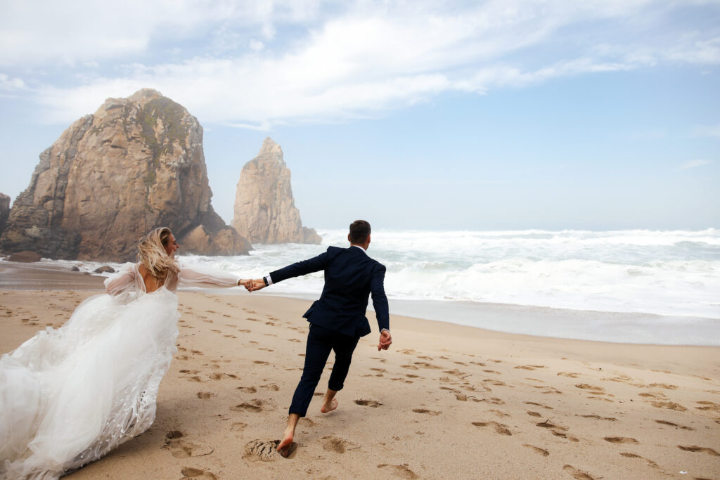 Newlywed couple running along beach