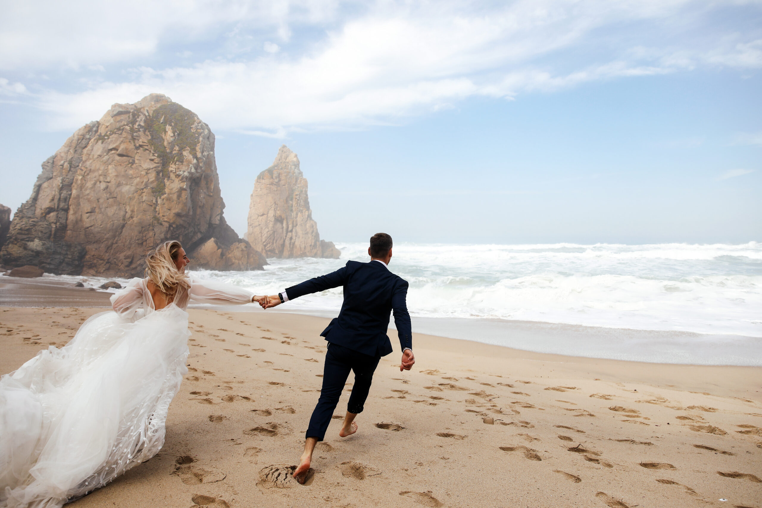Newlywed couple running along beach