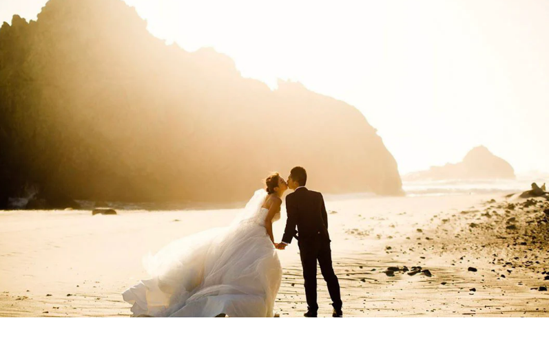 couple standing on a beach, in golden hours of sunset
