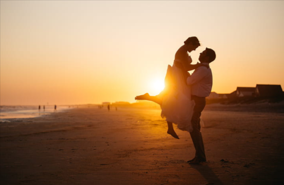 couple posing in the beach in the rustic glow of sunset 